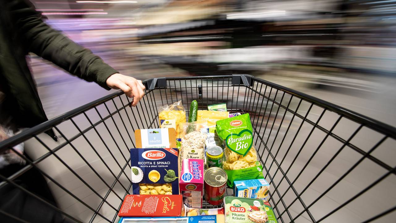 Ein Einkaufswagen wird durch einen Supermarkt geschoben.