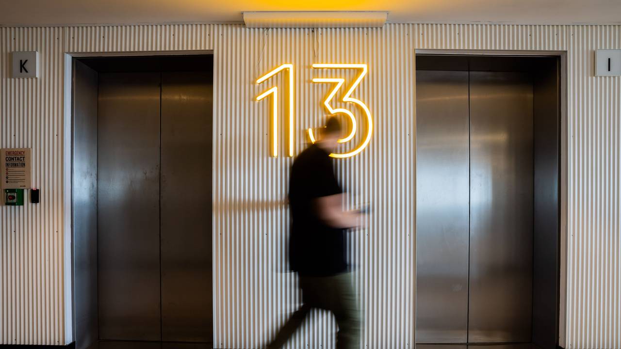 Ein Mann betätigt im 13. Stock einen Aufzug.