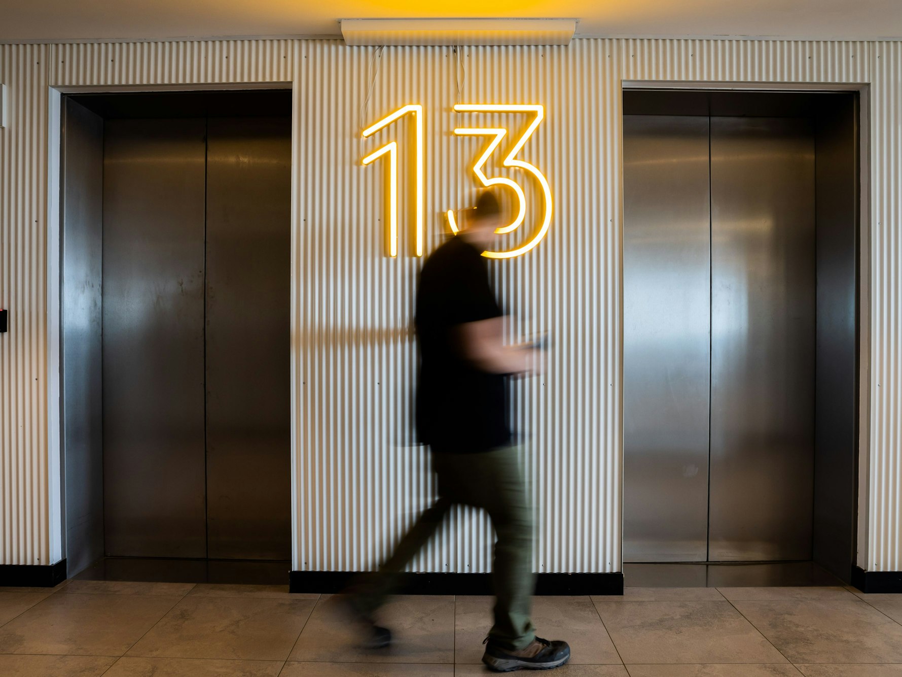 Ein Mann betätigt im 13. Stock einen Aufzug.