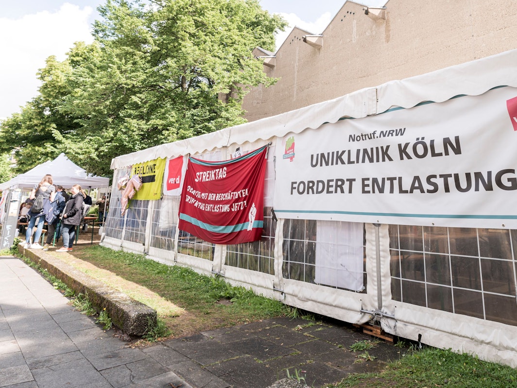 Streik an der Uniklinik in Köln, zu sehen ist ein Plakat auf einem Pavillon.