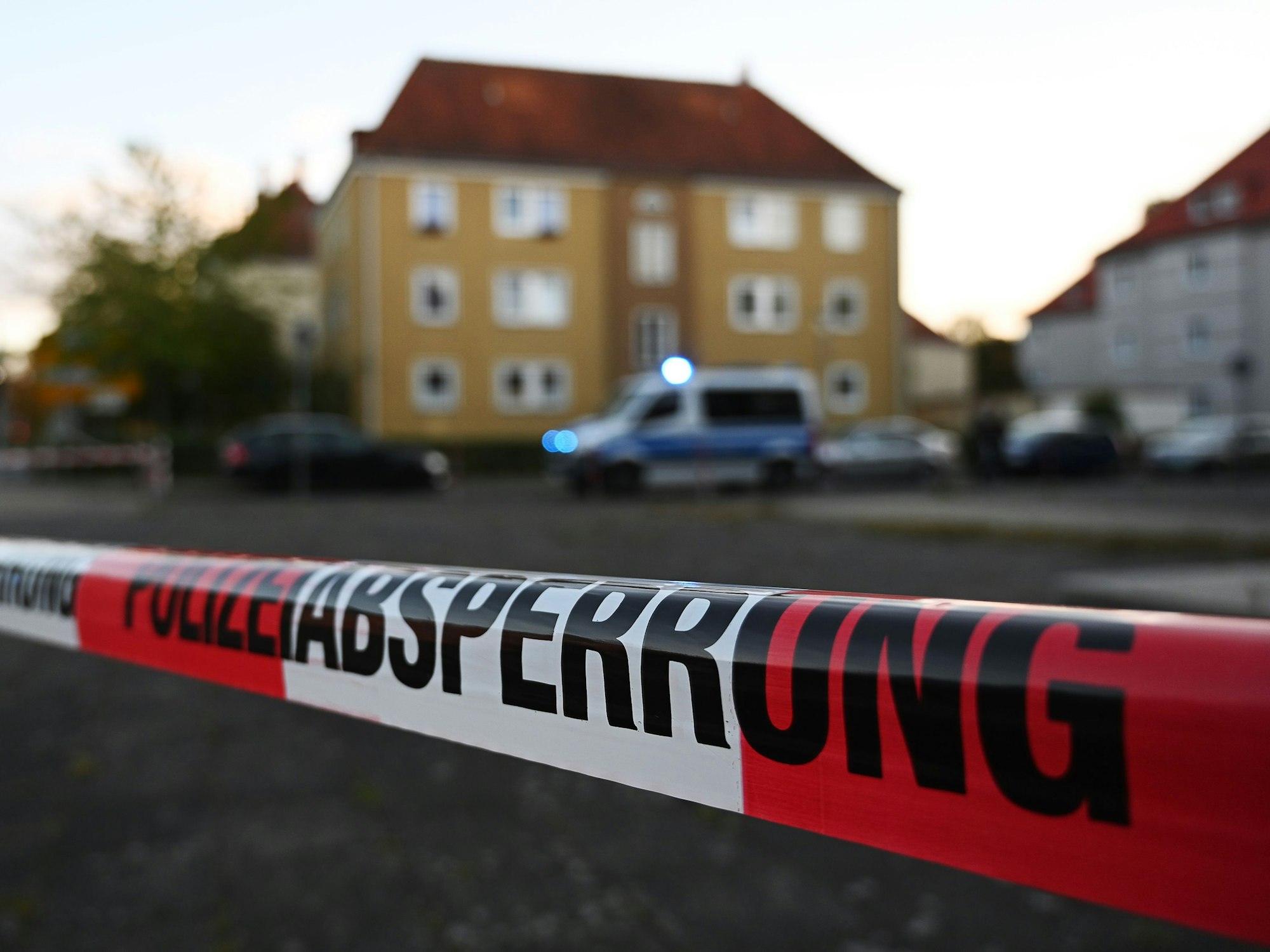 Absperrband mit der Aufschrift 'Polizeiabsperrung' ist vor einem Polizei-Auto.