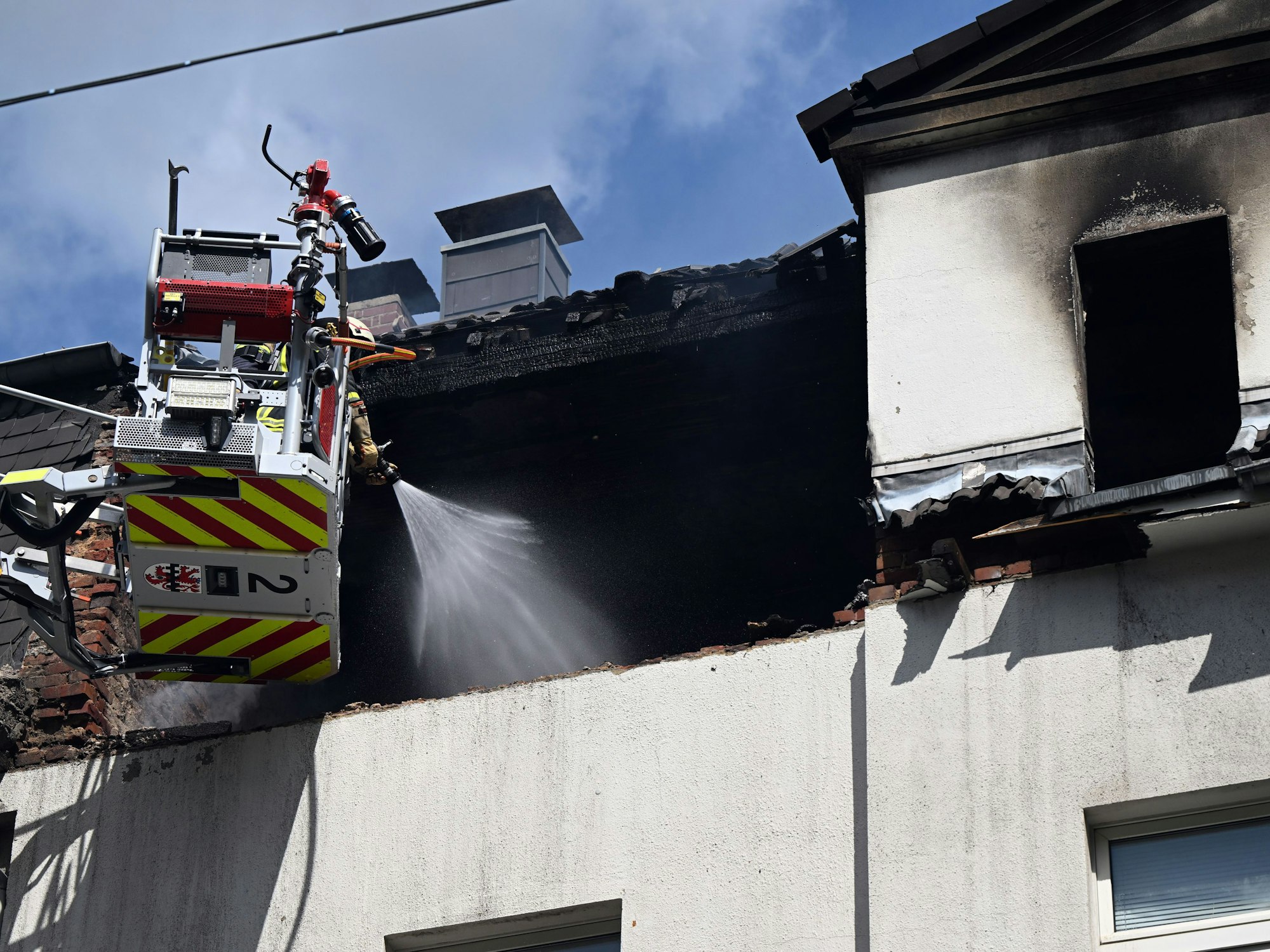 Feuerwehrleute löschen einen Brand in einem Dachstuhl. In einem Mehrfamilienhaus in Leverkusen hat es am Freitagmorgen eine Explosion gegeben.