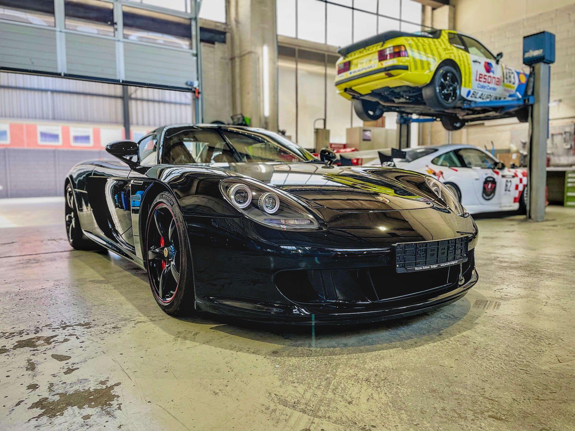Der Porsche Carrera GT von Michael Schumacher steht in einer Halle – im Hintergrund sind noch weitere Sportwagen zu sehen.
