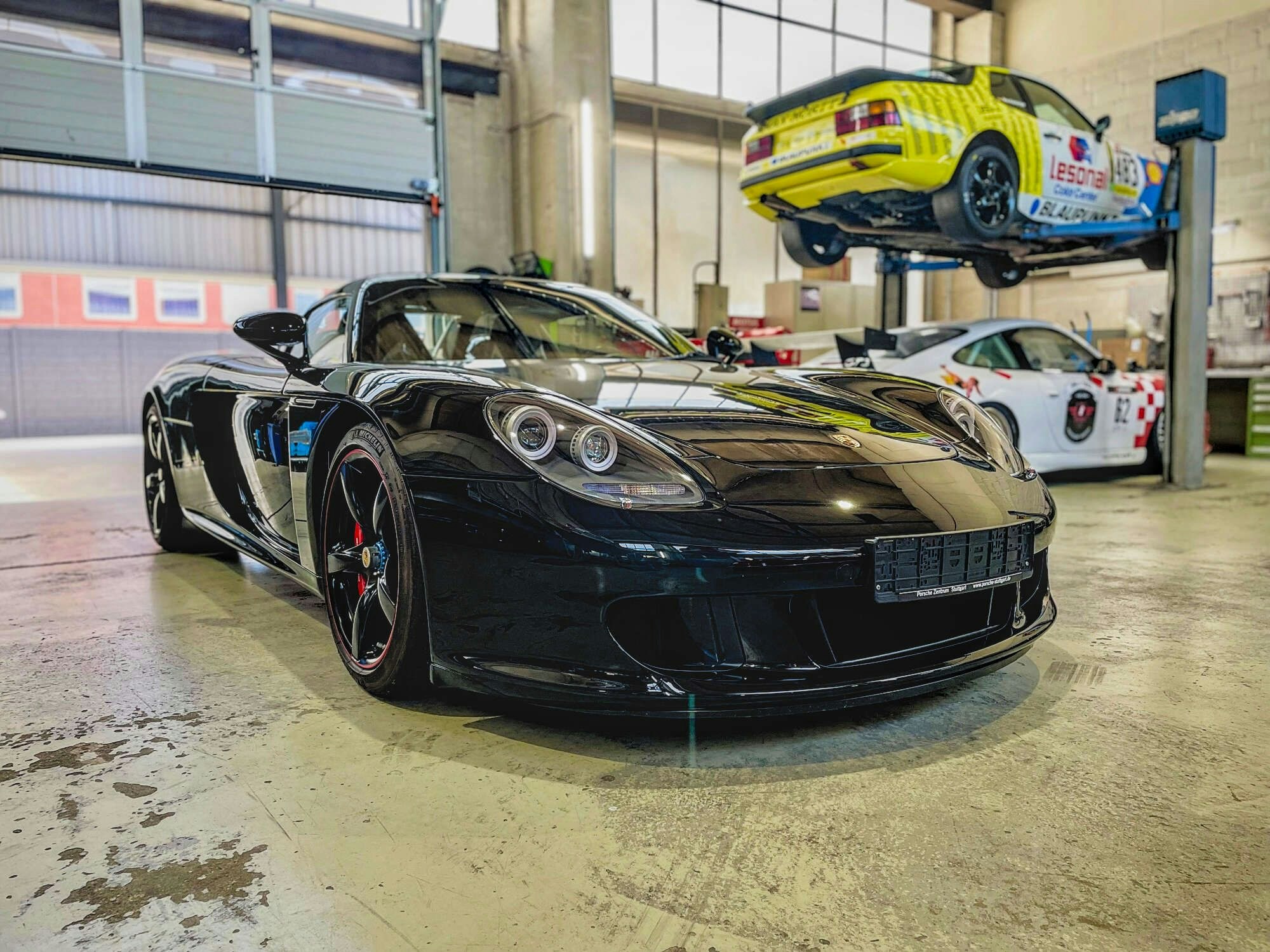 Der Porsche Carrera GT von Michael Schumacher steht in einer Halle – im Hintergrund sind noch weitere Sportwagen zu sehen.