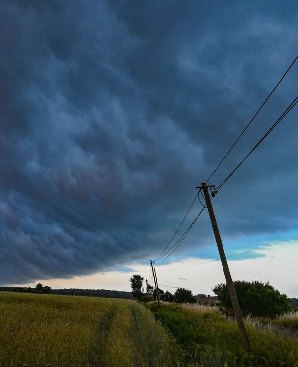 Am späten Abend zieht eine Gewitterzelle mit dunklen Regenwolken über die Landschaft.