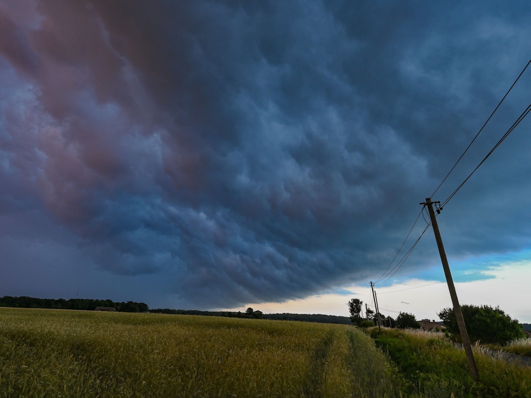 Am späten Abend zieht eine Gewitterzelle mit dunklen Regenwolken über die Landschaft.