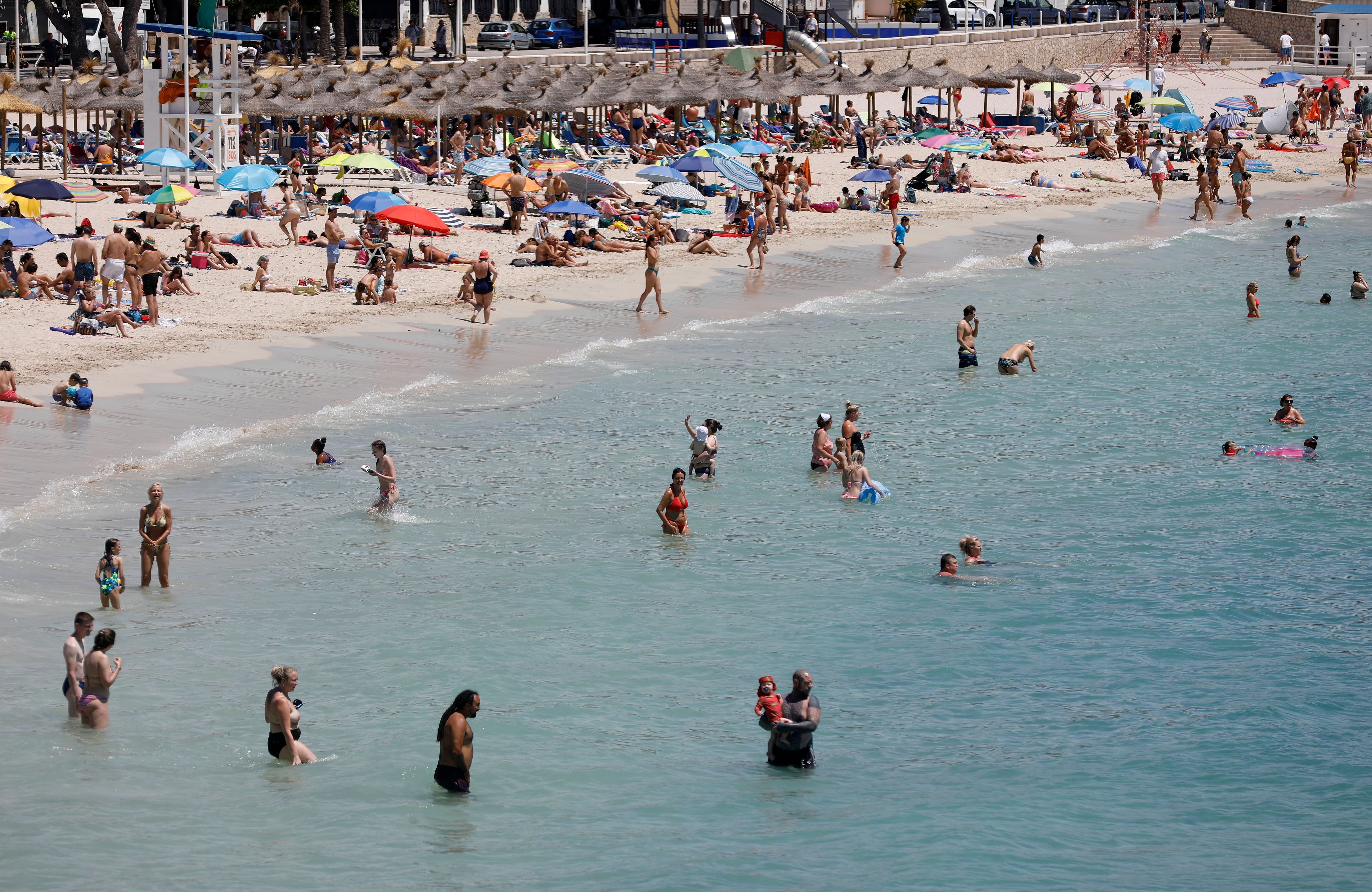 Menschen schwimmen und sonnen sich am Strand von Palmanova auf Mallorca.