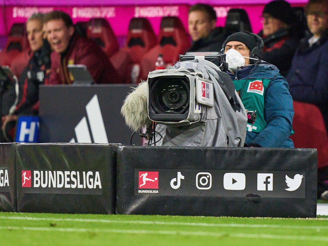 Ein Kameramann sitzt beim Bundesliga-Spiel gegen RB Leipzig vor der Bank des FC Bayern München