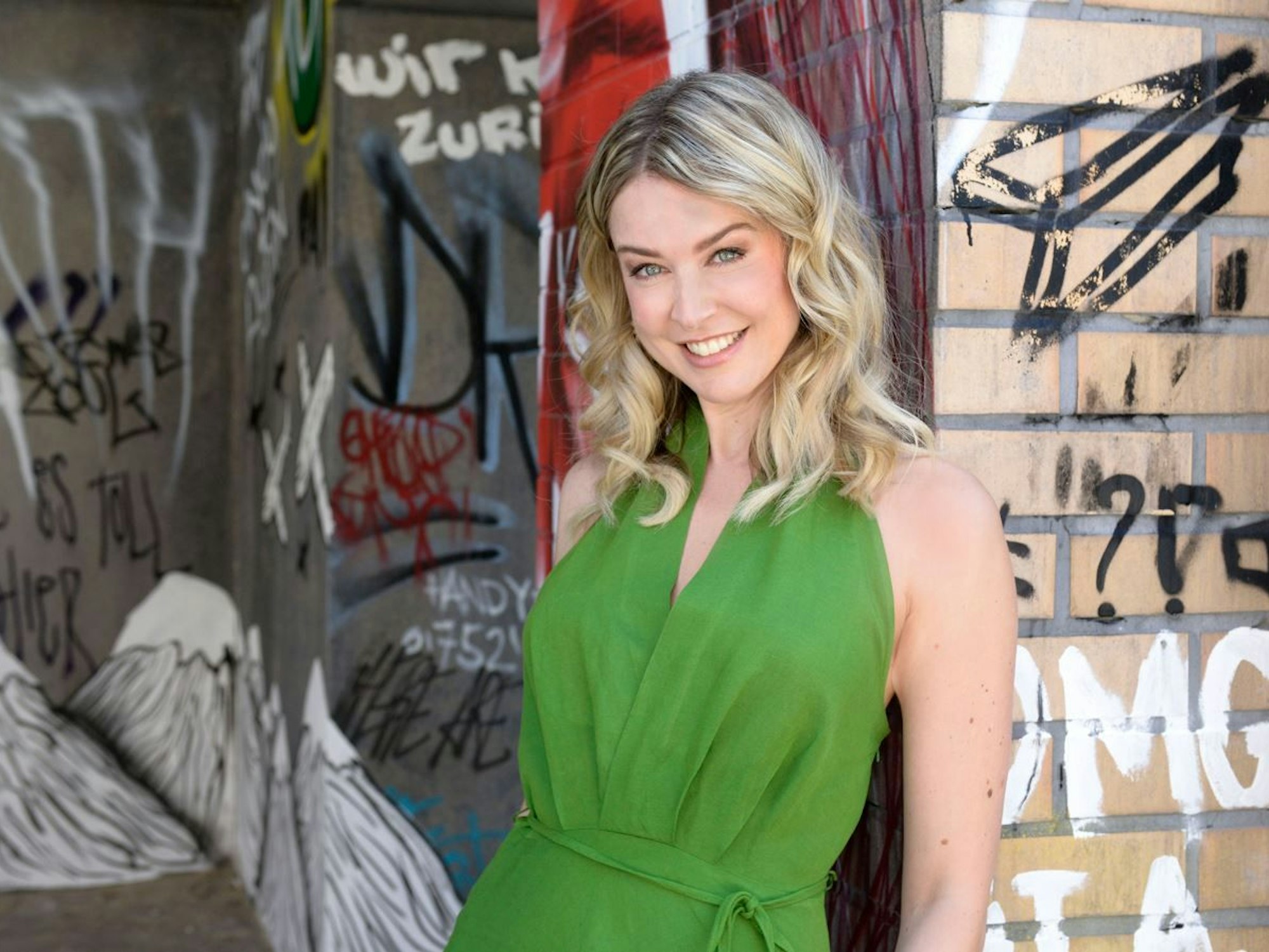 Schauspielerin Nina Ensmann vor einer Steinmauer fotografiert.