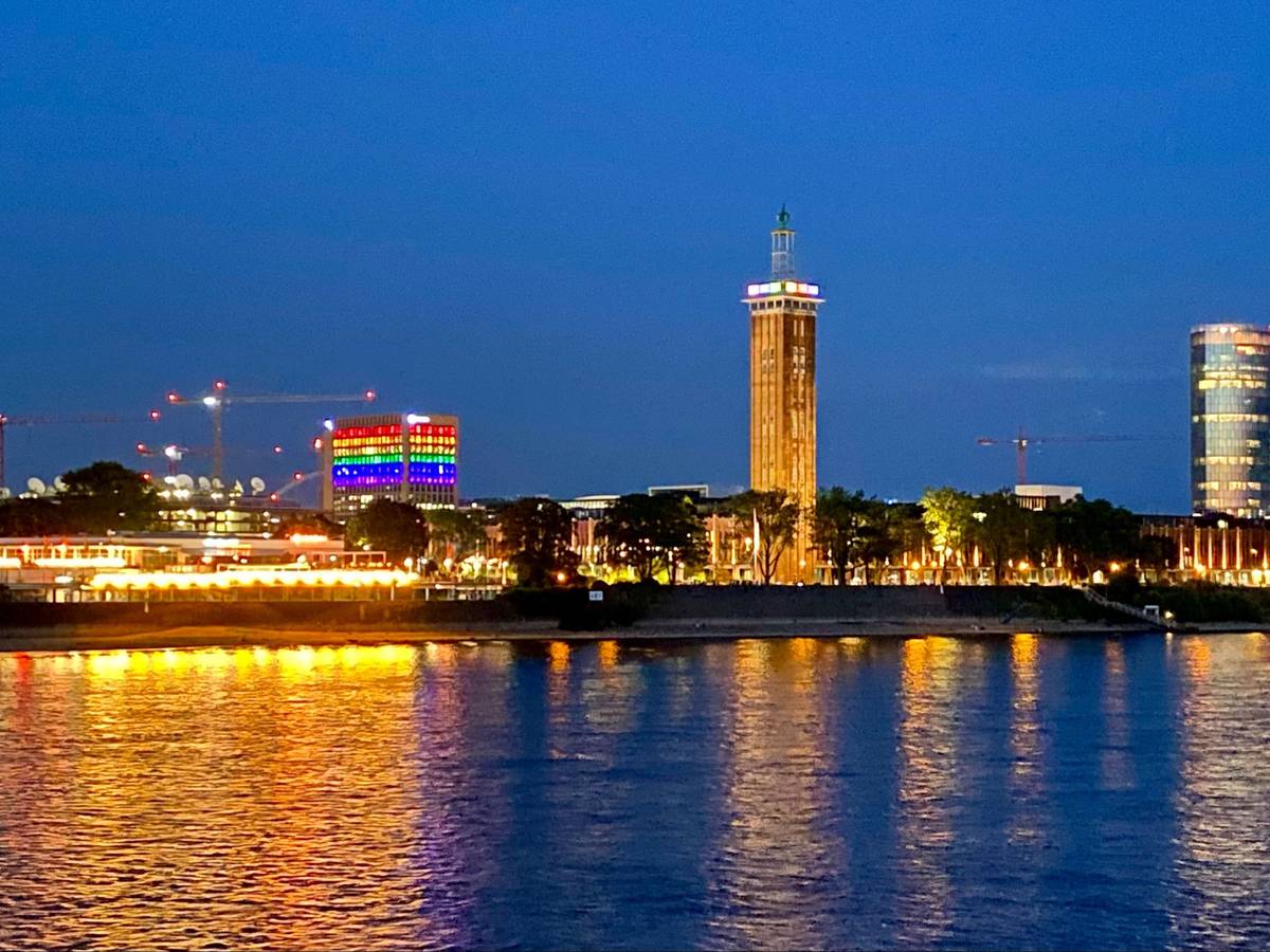 Ein Blick auf Köln-Deutz in der Dunkelheit. Ein Gebäude zeigt sich in Regenbogenfarben.