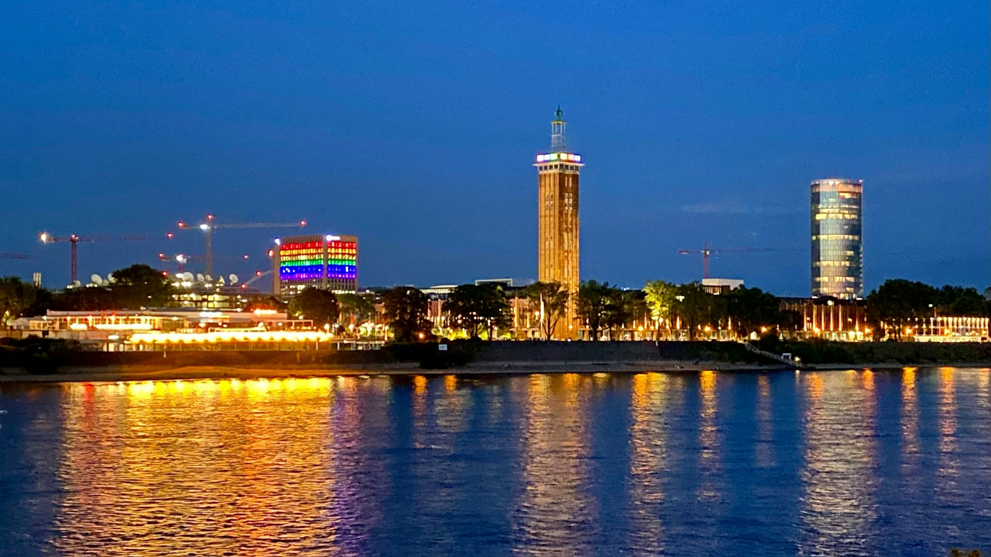 Ein Blick auf Köln-Deutz in der Dunkelheit. Ein Gebäude zeigt sich in Regenbogenfarben.