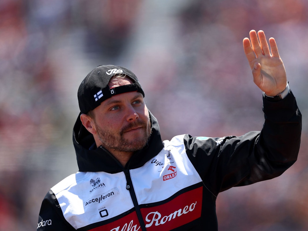 Valtteri Bottas hat eine Kappe verkehrt herum auf und winkt.