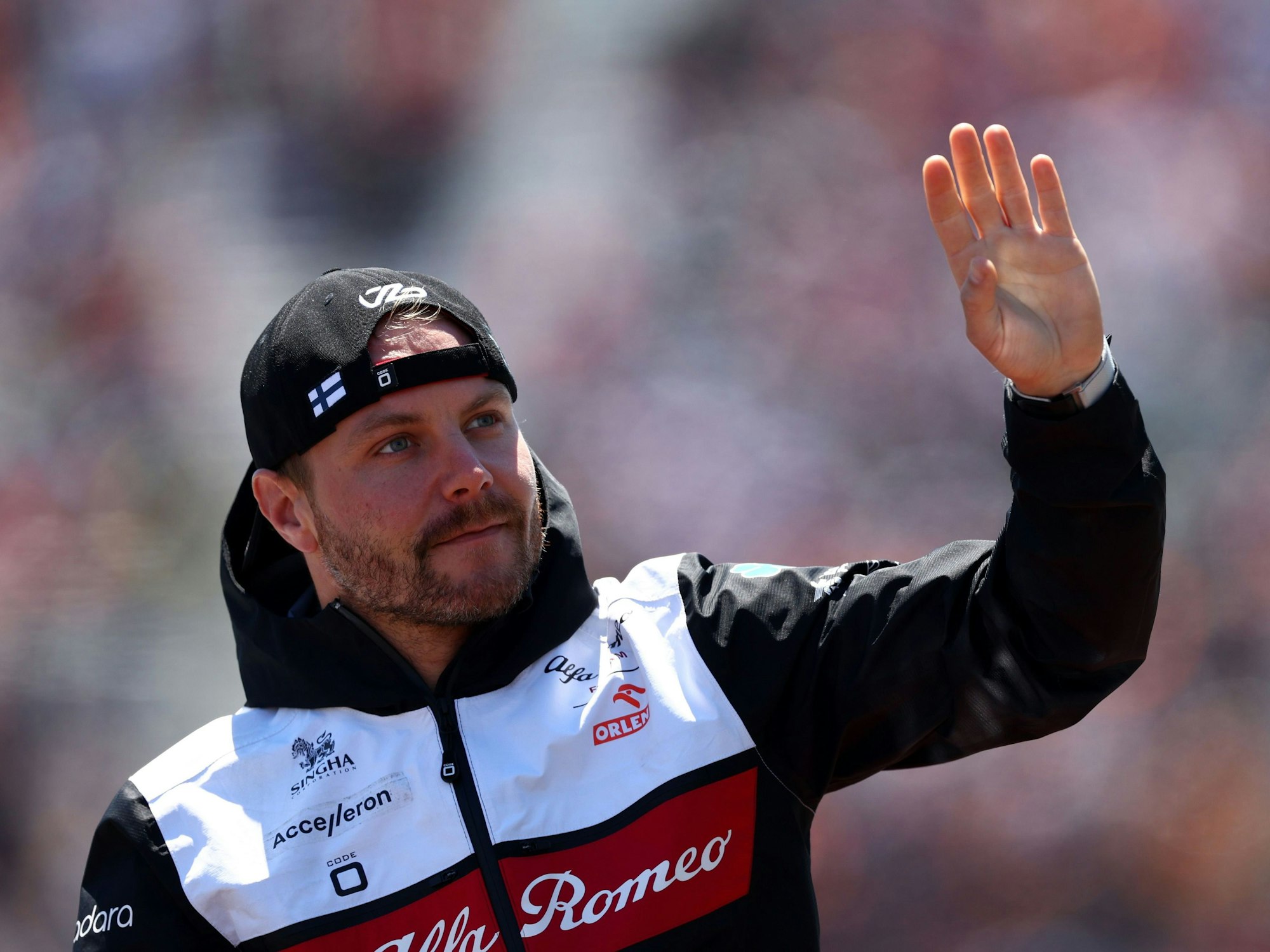 Valtteri Bottas hat eine Kappe verkehrt herum auf und winkt.