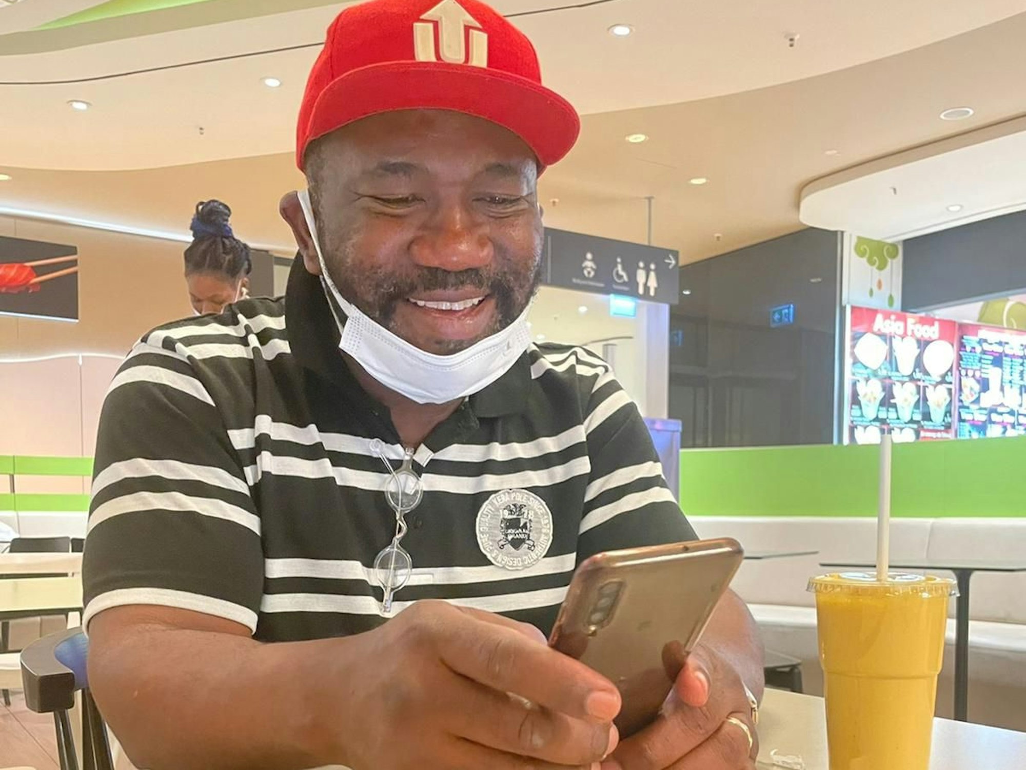 Joseph René Samnick (55) sitzt mit Handy an einem Tisch. Er wurde in einem Obdachlosenheim in Köln massiv rassistisch beleidigt.