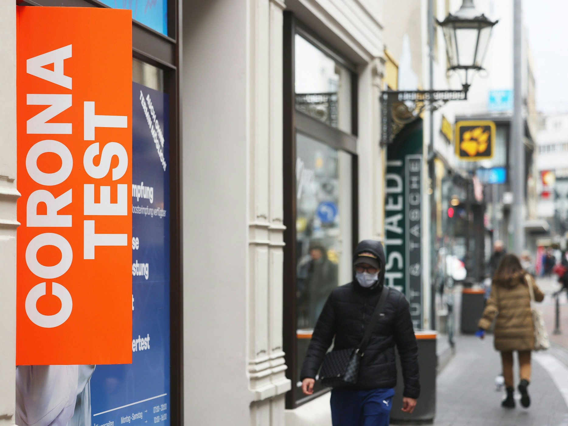 Fußgänger gehen an einer Teststation in der Bonner Innenstadt vorbei.