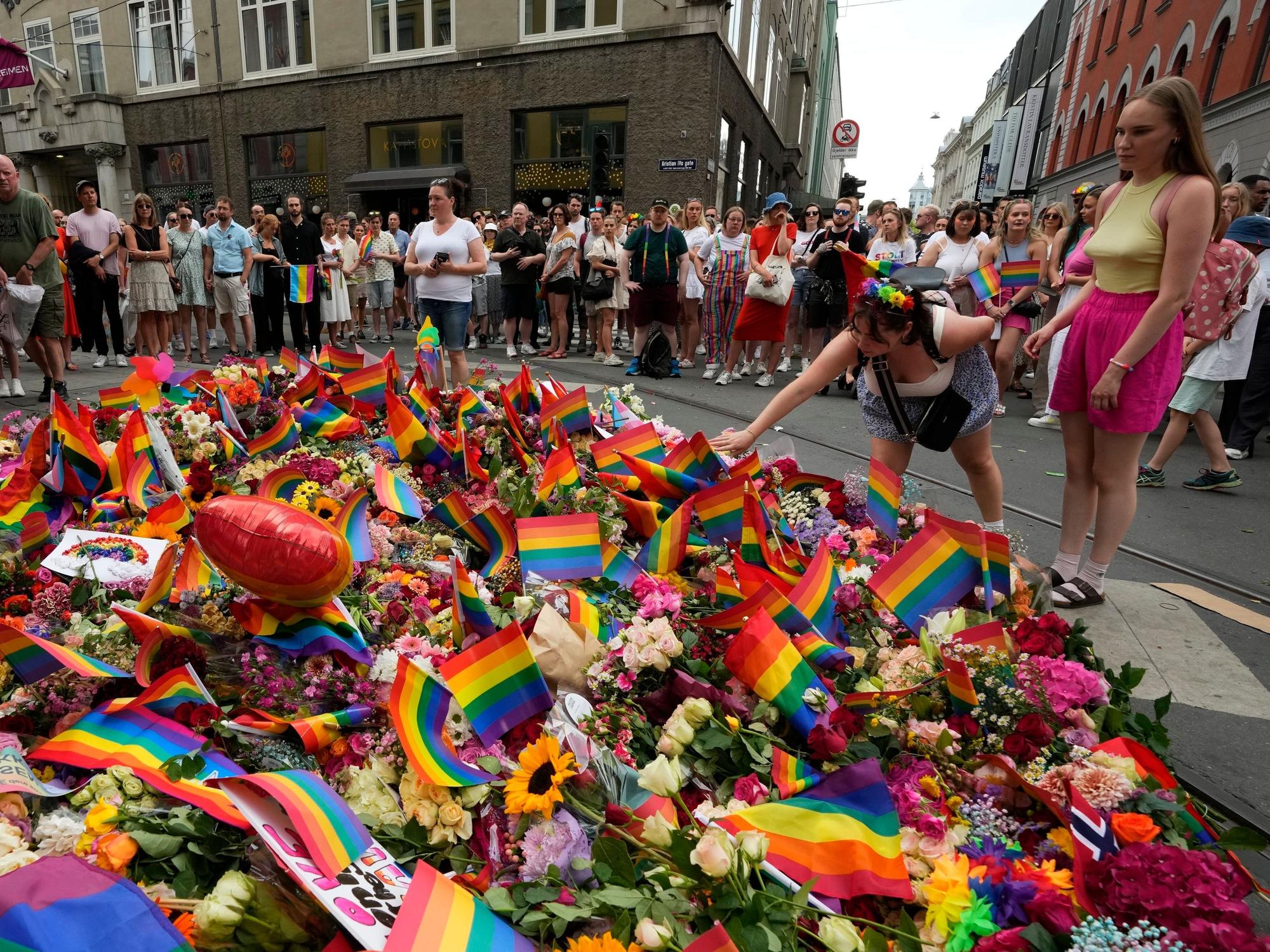Menschen legen am Samstag, 25. Juni 2022, am Ort der Schießerei im Zentrum von Oslo Blumen nieder. Ein Schütze eröffnete am frühen Samstag das Feuer im Ausgehviertel von Oslo und tötete zwei Menschen.