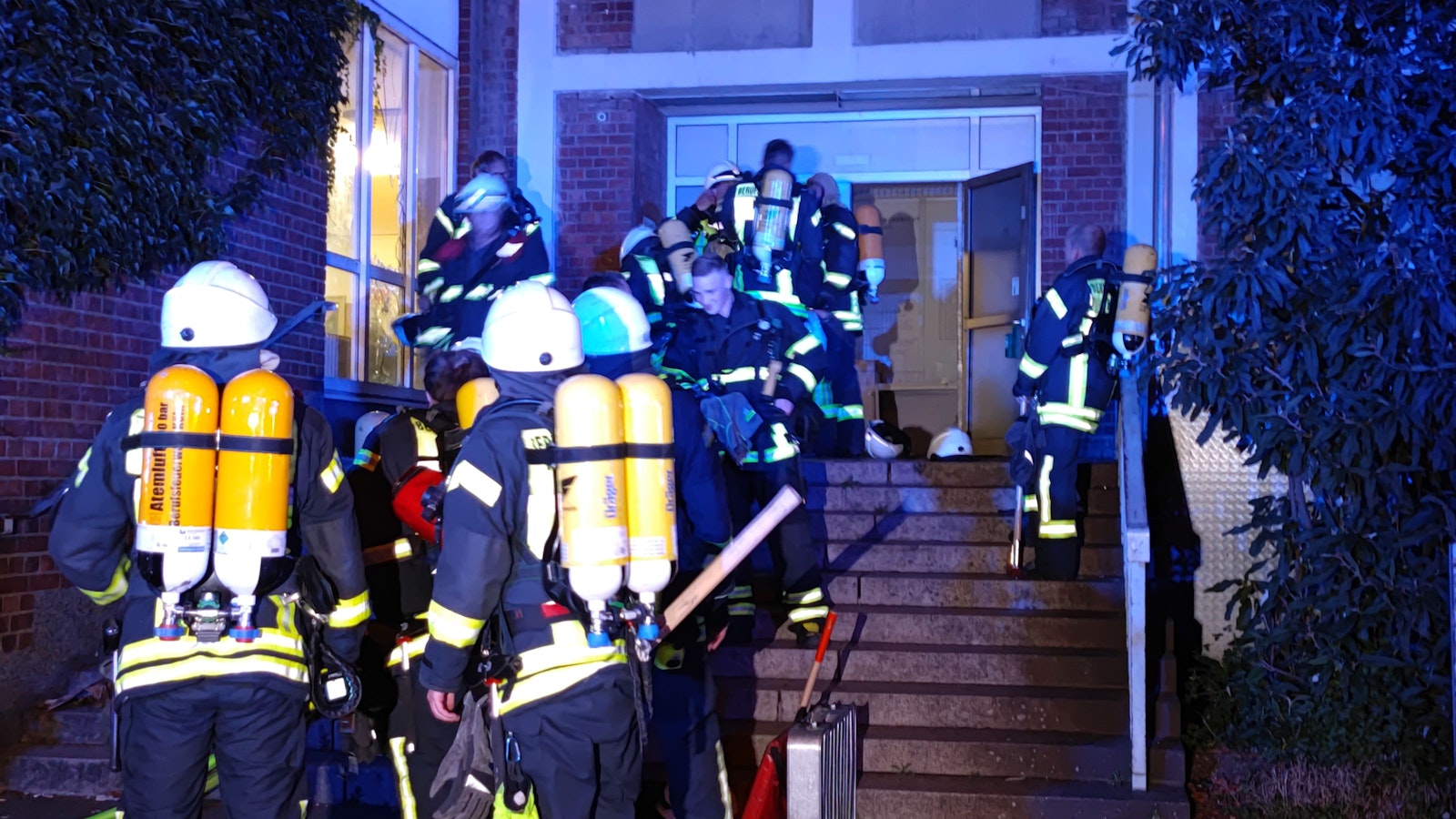 Feuerwehrleute betreten ein Gebäude.
