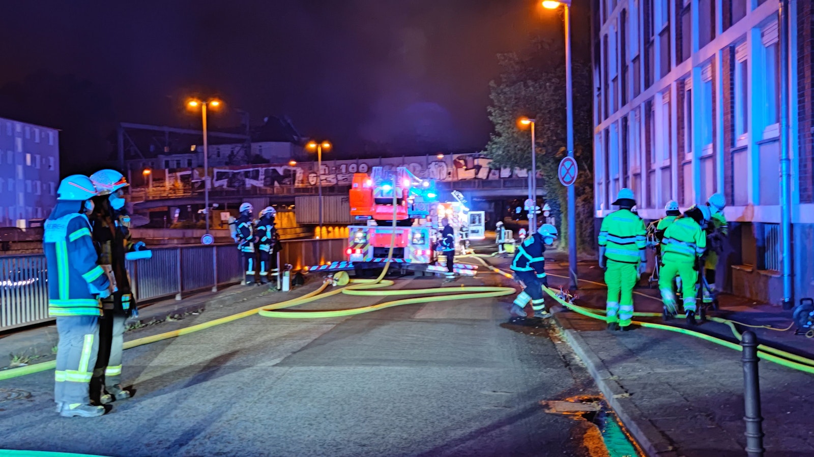 Feuerwehrleute verlegen Wasserschläuche bei einem Einsatz.