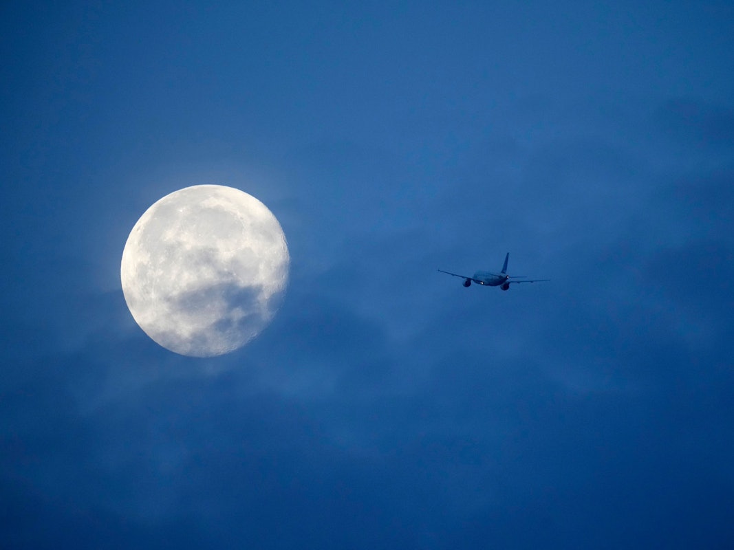 Der Mond ist hinter einem Flugzeug zu sehen