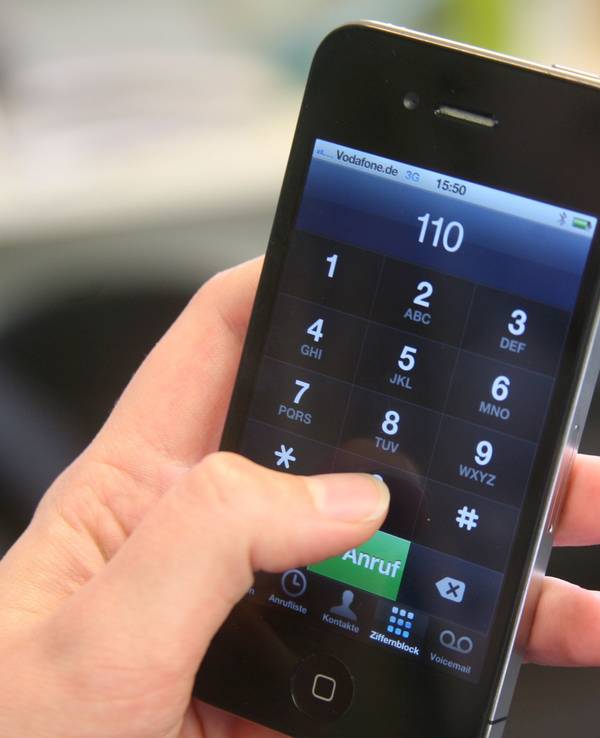 Eine junge Frau hält ein Smartphone mit der eingegebenen Notrufnummer 110 in der Hand.