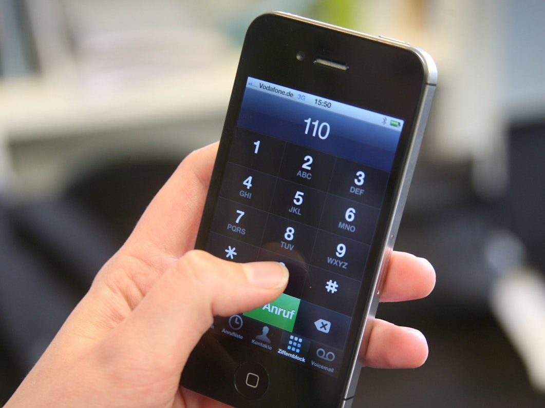 Eine Frau hält ein Smartphone mit der eingegebenen Notrufnummer 110 in der Hand.