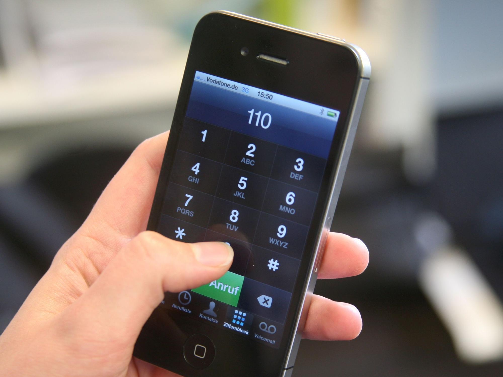 Eine Frau hält ein Smartphone mit der eingegebenen Notrufnummer 110 in der Hand.
