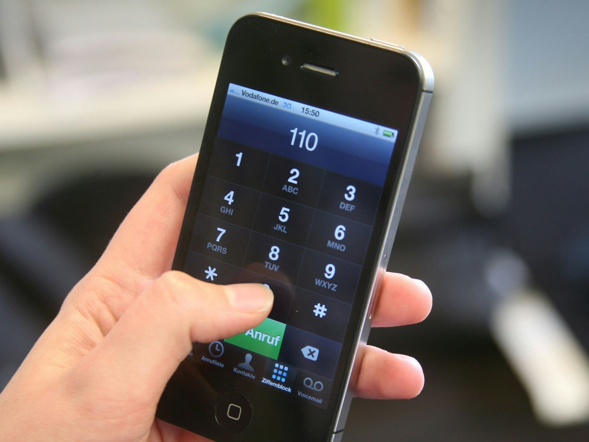 Eine Frau hält ein Smartphone mit der eingegebenen Notrufnummer 110 in der Hand.