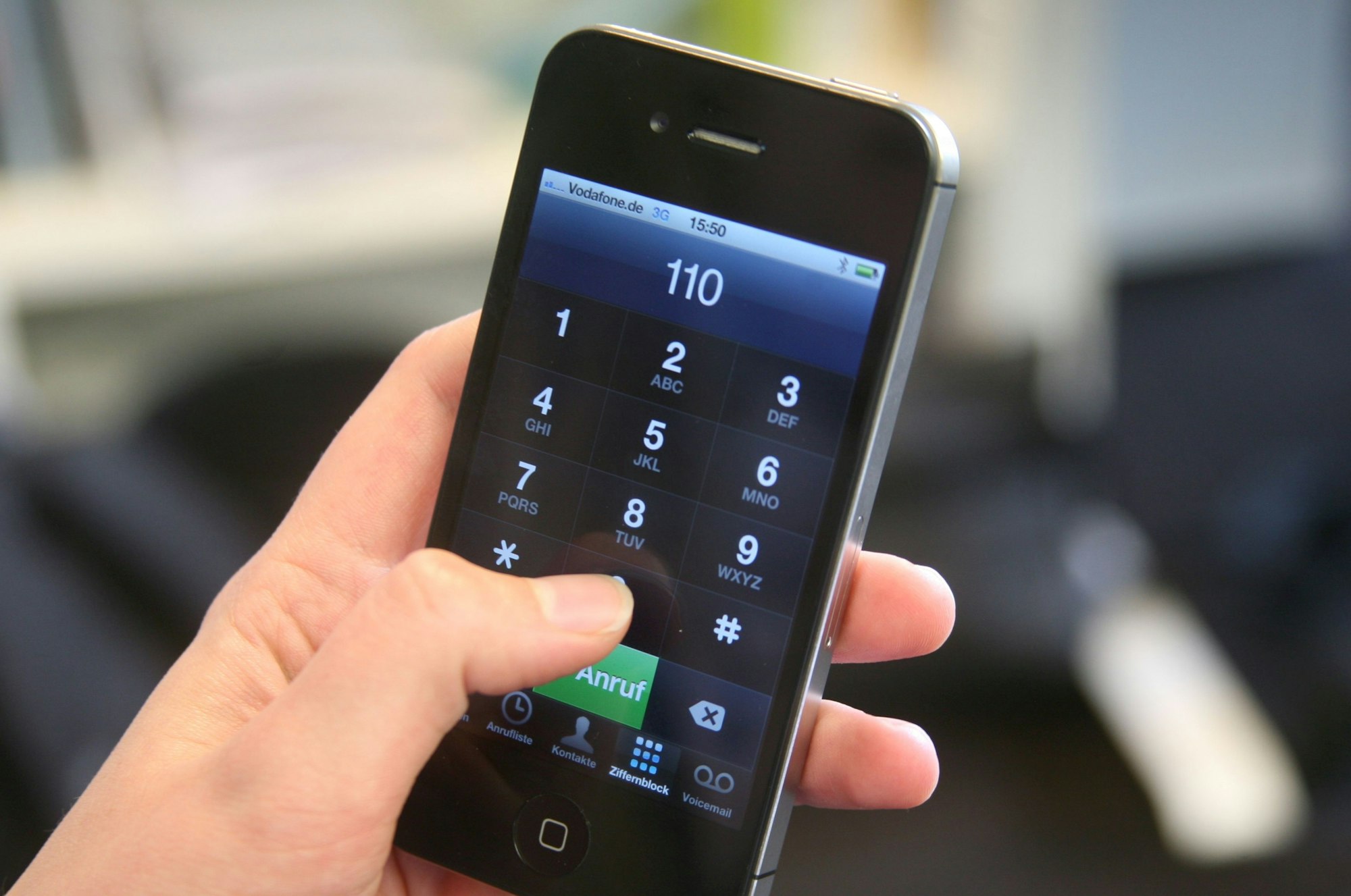 Eine junge Frau hält ein Smartphone mit der eingegebenen Notrufnummer 110 in der Hand.