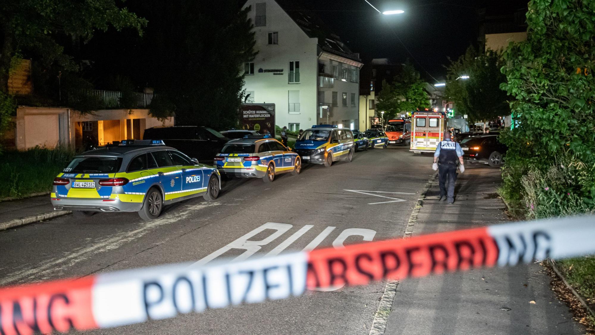 Polizeiautos stehen auf einer Straße hinter Absperrband.