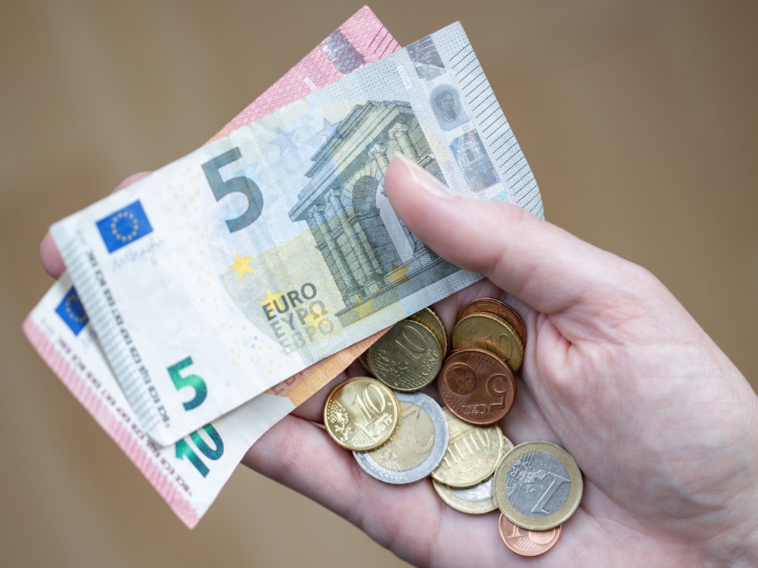 Eine Frau hält Geldscheine und Münzen in der Hand.