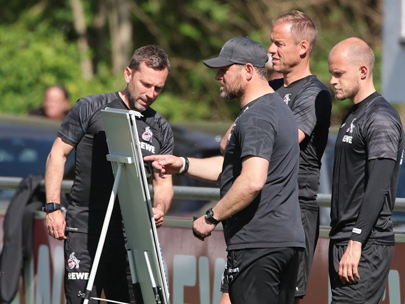 Steffen Baumgart steht mit seinen Assistenten André Pawlak, Kevin McKenna und René Wagner beim Training des 1. FC Köln vor einer Taktik-Tafel.