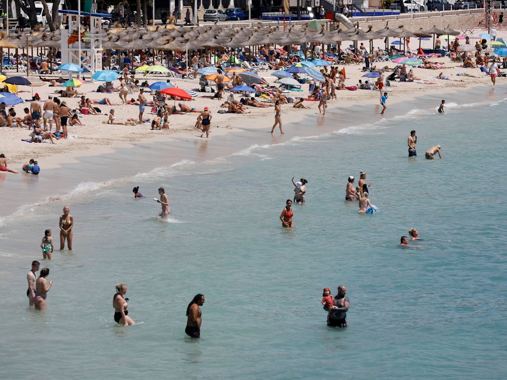 Menschen schwimmen und sonnen sich am Strand von Palmanova auf Mallorca.