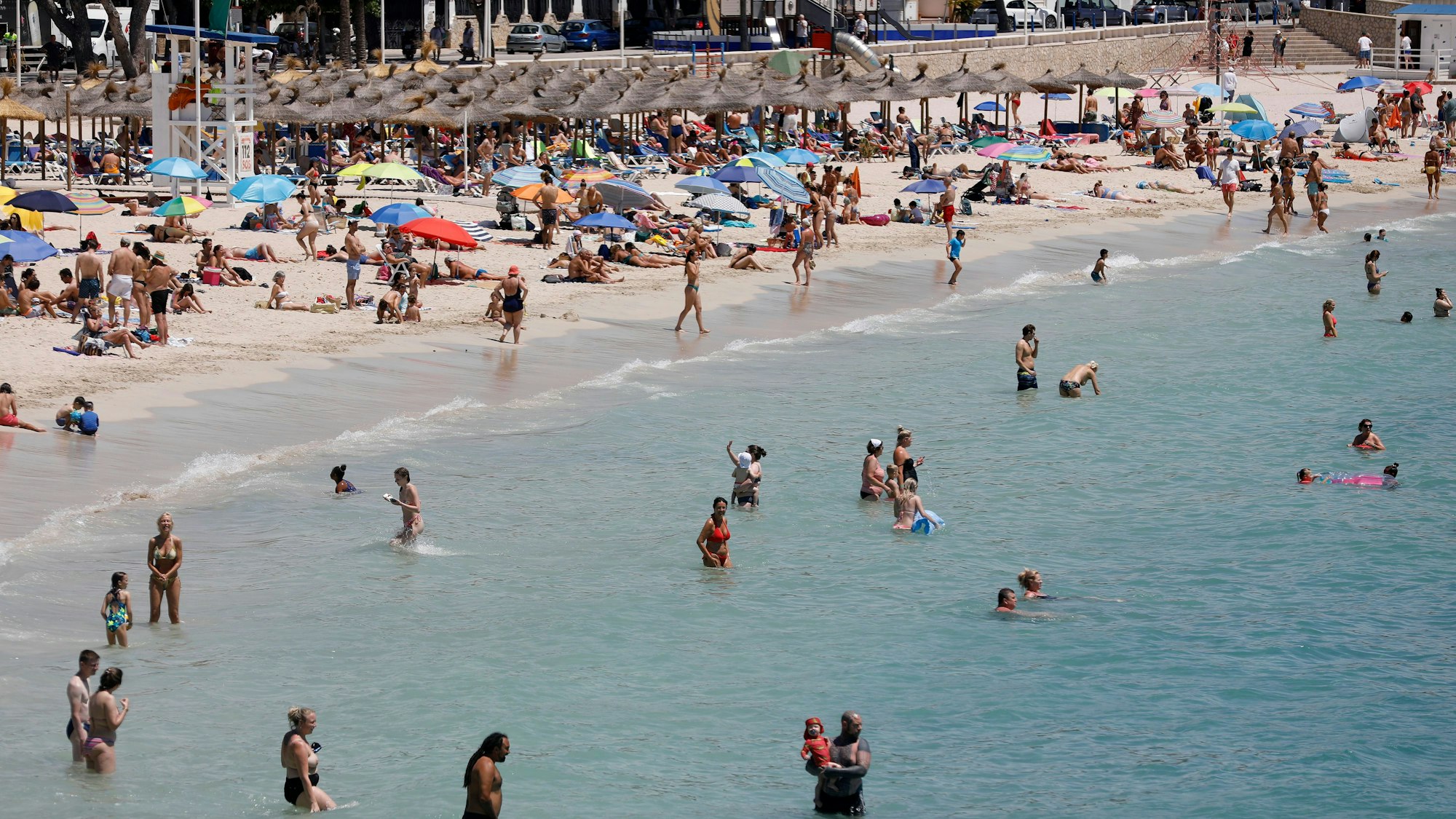 Menschen schwimmen und sonnen sich am Strand von Palmanova auf Mallorca.