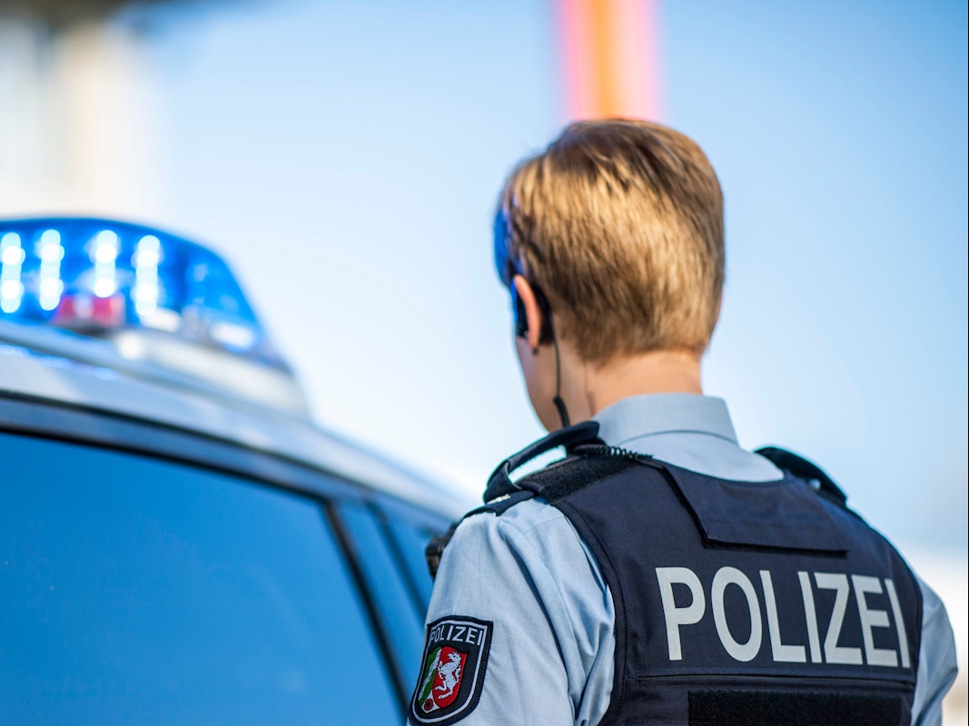 Eine Polizistin steht am 28. September 2021 vor einem Streifenwagen, dessen Blaulicht leuchtet.