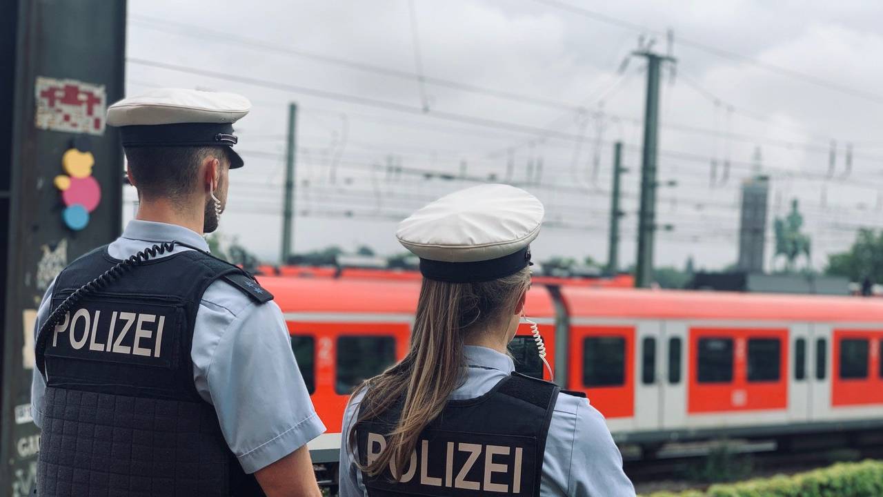 Das Foto zeigt eine Polizistin und einen Polizisten, die die Bahngleise beobachten.