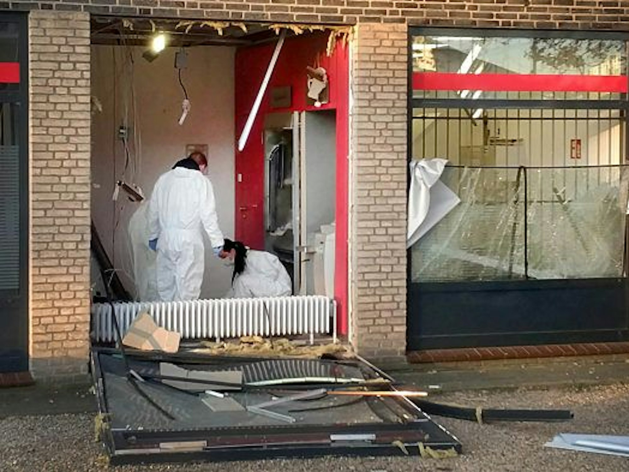 Eine Beamtin und ein Beamter in Schutzanzügen untersuchen den Tatort nach einer Geldautomatensprengung in NRW.