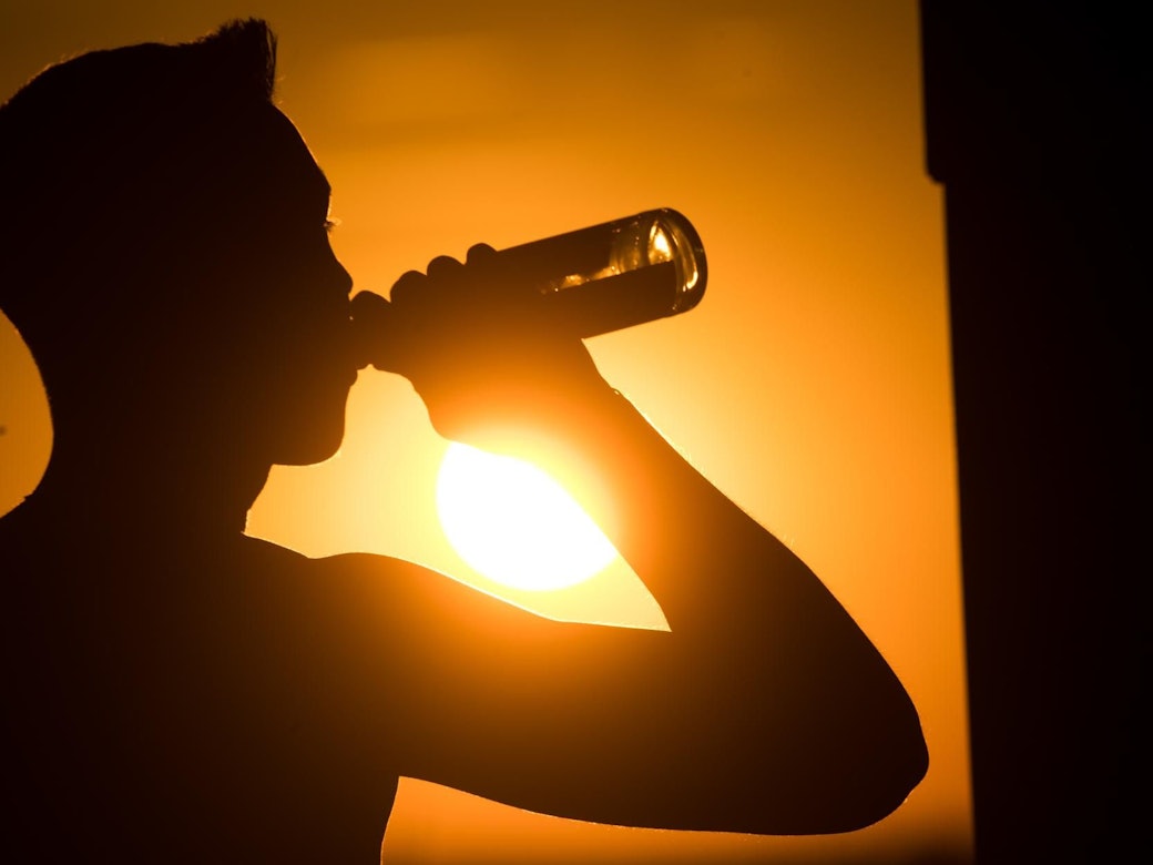 Eine spanische Biermarke hat sich eine besondere Aktion für alle Spanien-Urlaubenden ausgedacht, die unter dem Flug-Chaos leiden müssen. Das Symbolbild zeigt eine Person, die im Sonnenuntergang eine Flasche Bier trinkt.