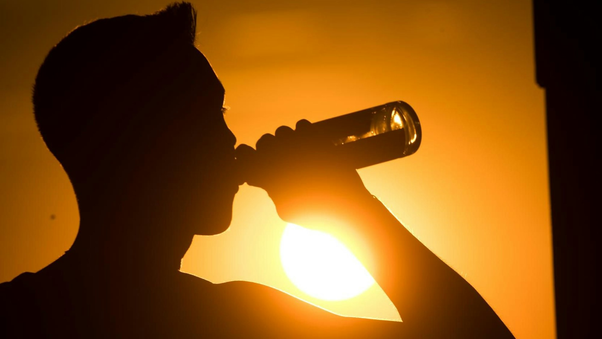 Eine spanische Biermarke hat sich eine besondere Aktion für alle Spanien-Urlaubenden ausgedacht, die unter dem Flug-Chaos leiden müssen. Das Symbolbild zeigt eine Person, die im Sonnenuntergang eine Flasche Bier trinkt.