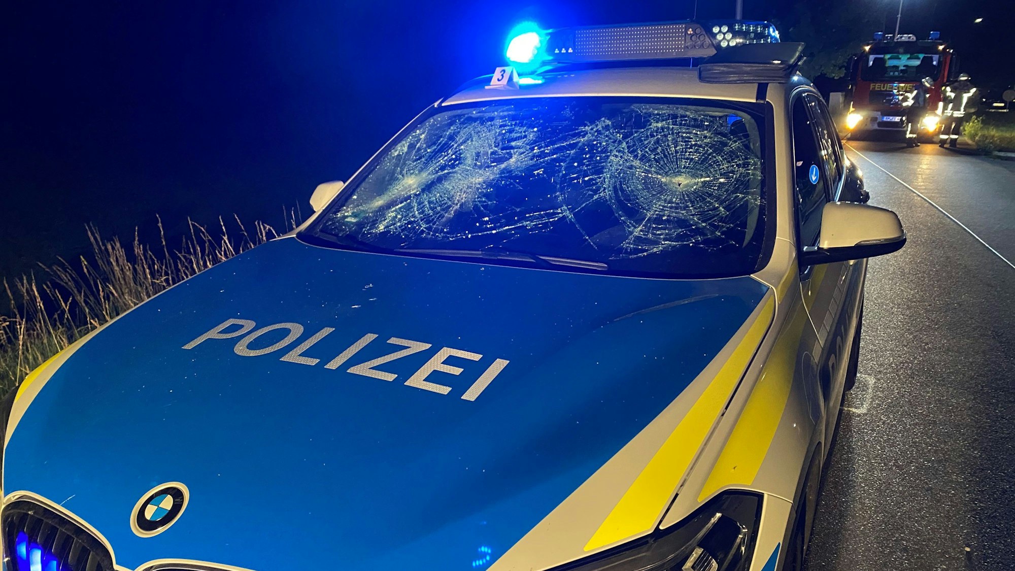Ein Streifenwagen der Polizei steht mit einer von einem Angreifer zerstörten Windschutzscheibe am Straßenrand in Amberg
