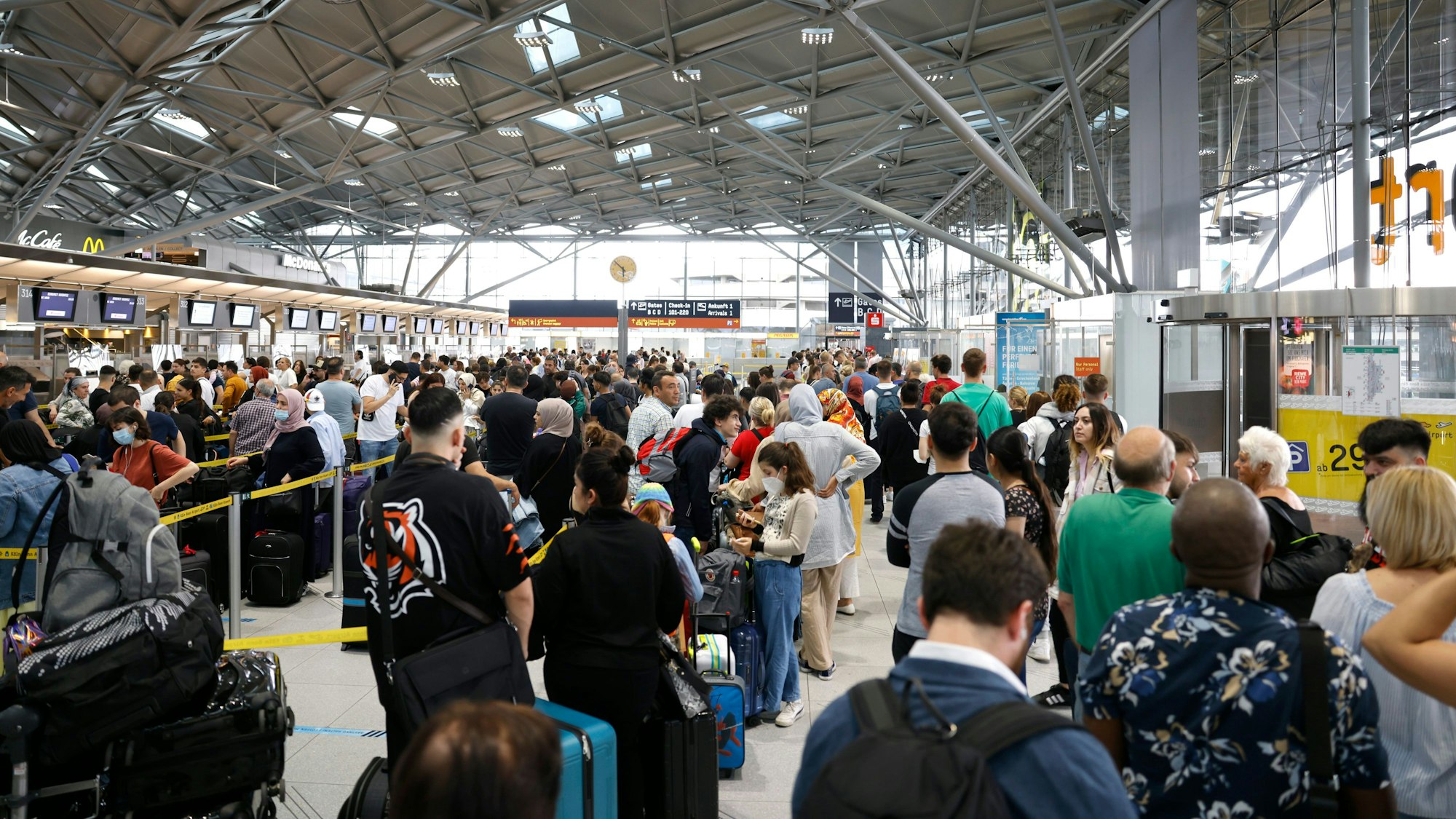 Passagiere stehen in einer Schlange von mehreren hundert Metern für die Sicherheitskontrolle am Flughafen Köln-Bonn an.
