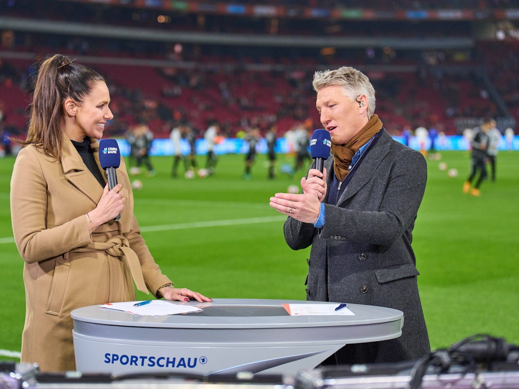 Esther Sedlaczek und Bastian Schweinsteiger im Gespräch am Spielfeldrand.