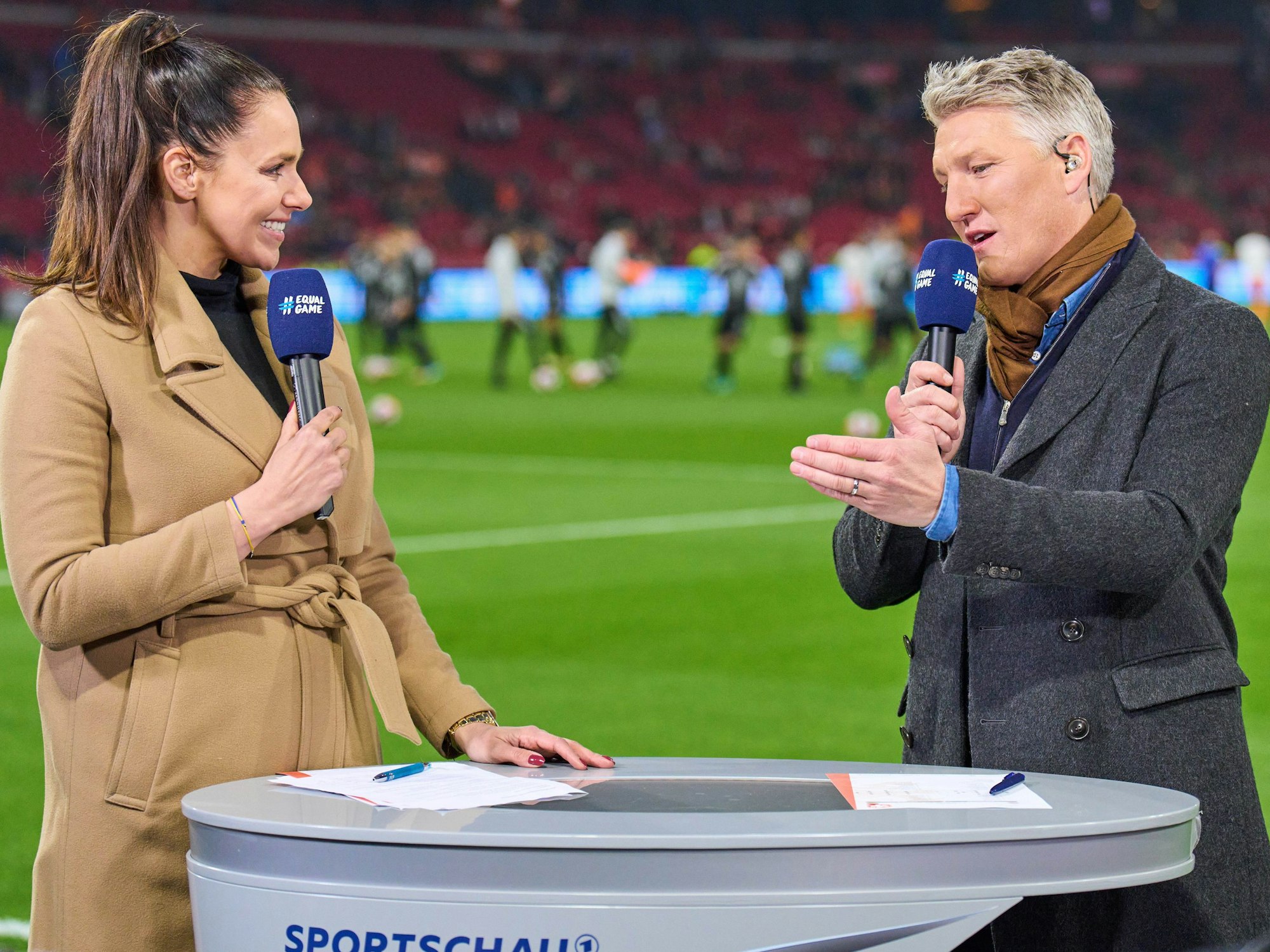 Esther Sedlaczek und Bastian Schweinsteiger im Gespräch am Spielfeldrand.