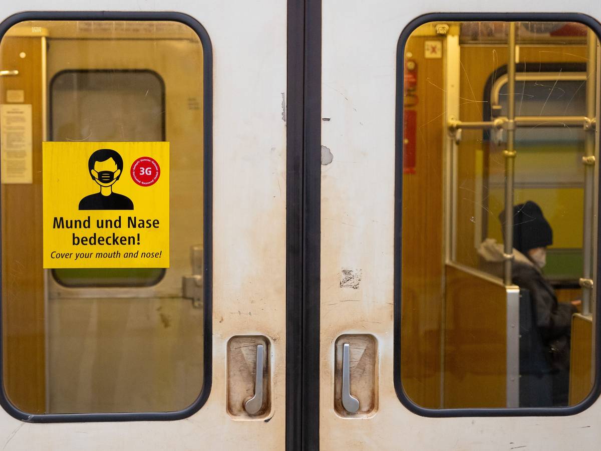 Ein Aufkleber mit der Aufschrift „Mund und Nase bedecken!“ ist an einer U-Bahn angebracht.