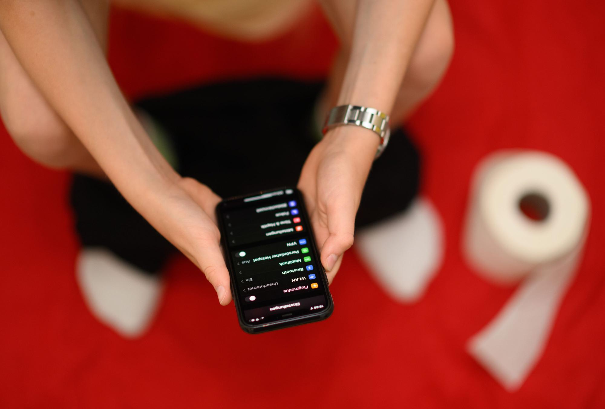 30.06.2022, Sachsen, Dresden: Eine Junge hält auf der Toilette sein Smartphone in den Händen. Immer mehr Deutsche nehmen ihr Smartphone mit auf die Toilette.