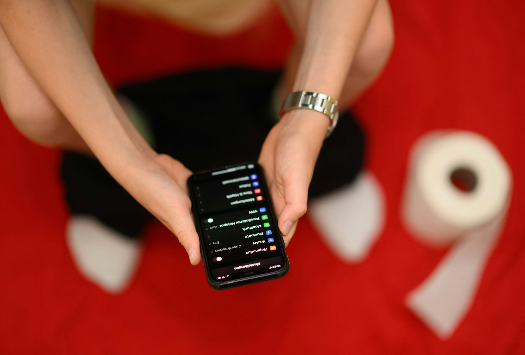 30.06.2022, Sachsen, Dresden: Eine Junge hält auf der Toilette sein Smartphone in den Händen. Immer mehr Deutsche nehmen ihr Smartphone mit auf die Toilette.