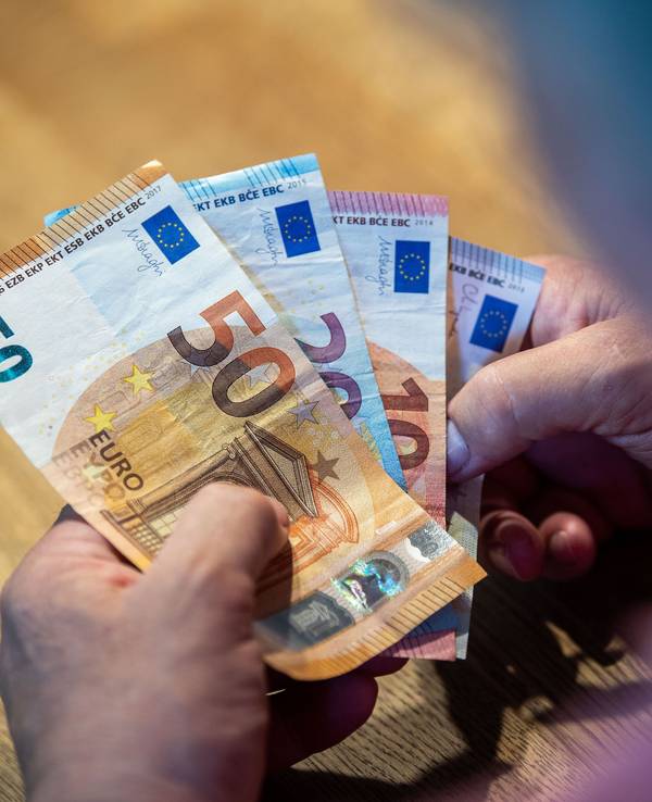 Ein älterer Mann sitzt an einem Tisch und zählt Geld, die Aufnahme dient als Symbolfoto.