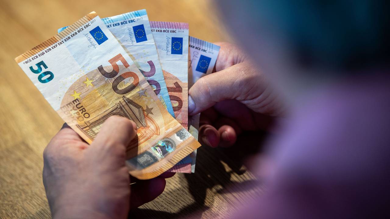 Ein älterer Mann sitzt an einem Tisch und zählt Geld, die Aufnahme dient als Symbolfoto.