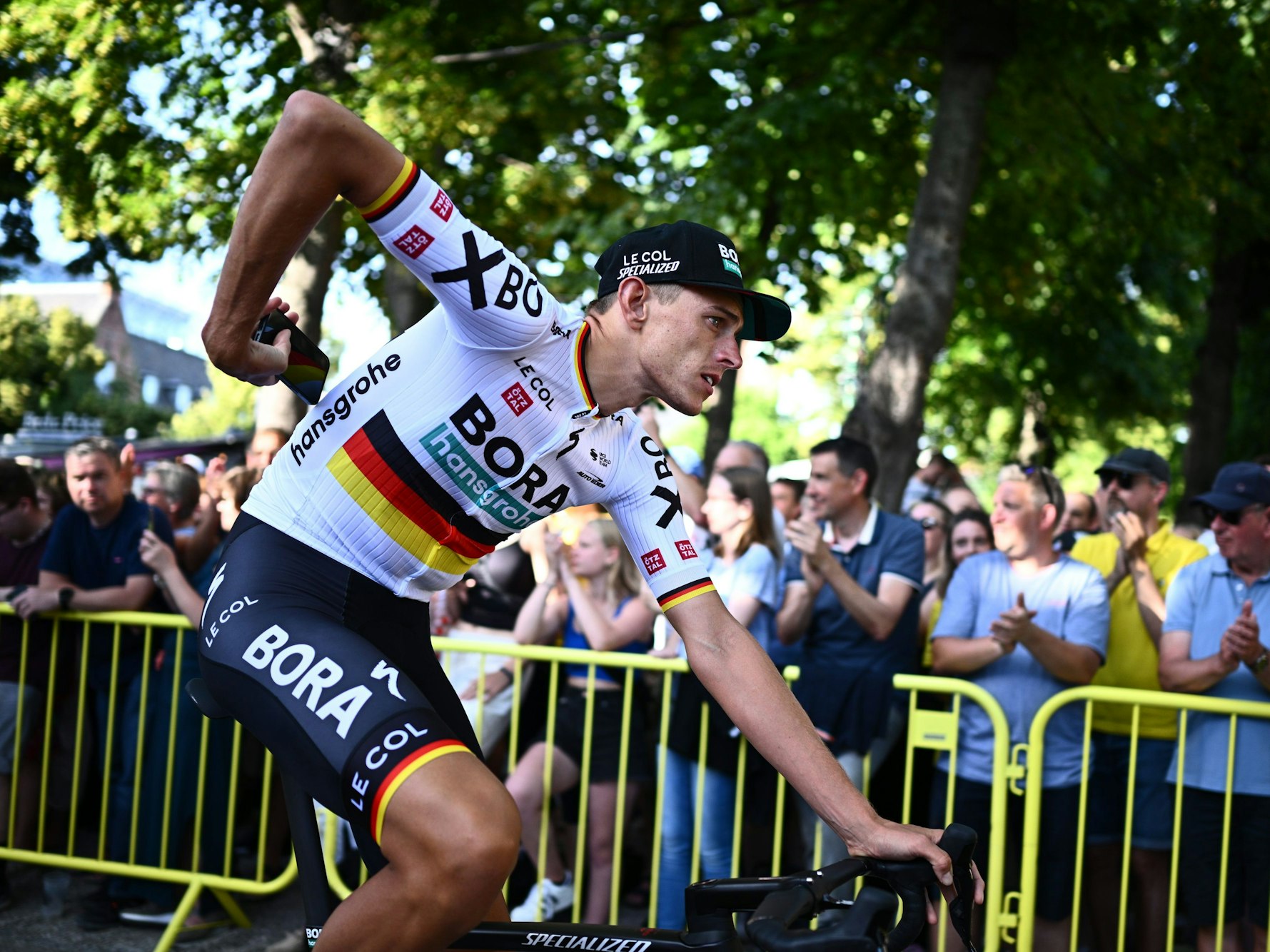 Nils Politt fährt mit einem Handy in der Hand an Zuschauern vorbei.
