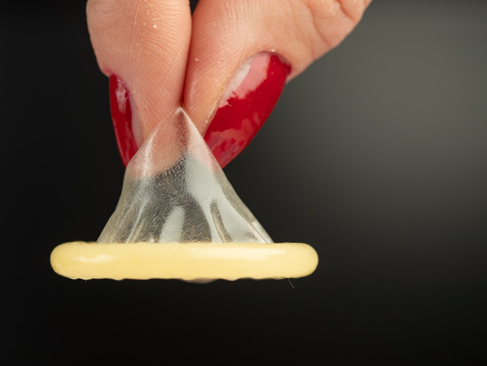 Eine Frau hält auf dem undatierten Symbolbild ein Kondom mit zwei Fingern. Forscher haben das Affenpocken-Virus in Sperma nachgewiesen.