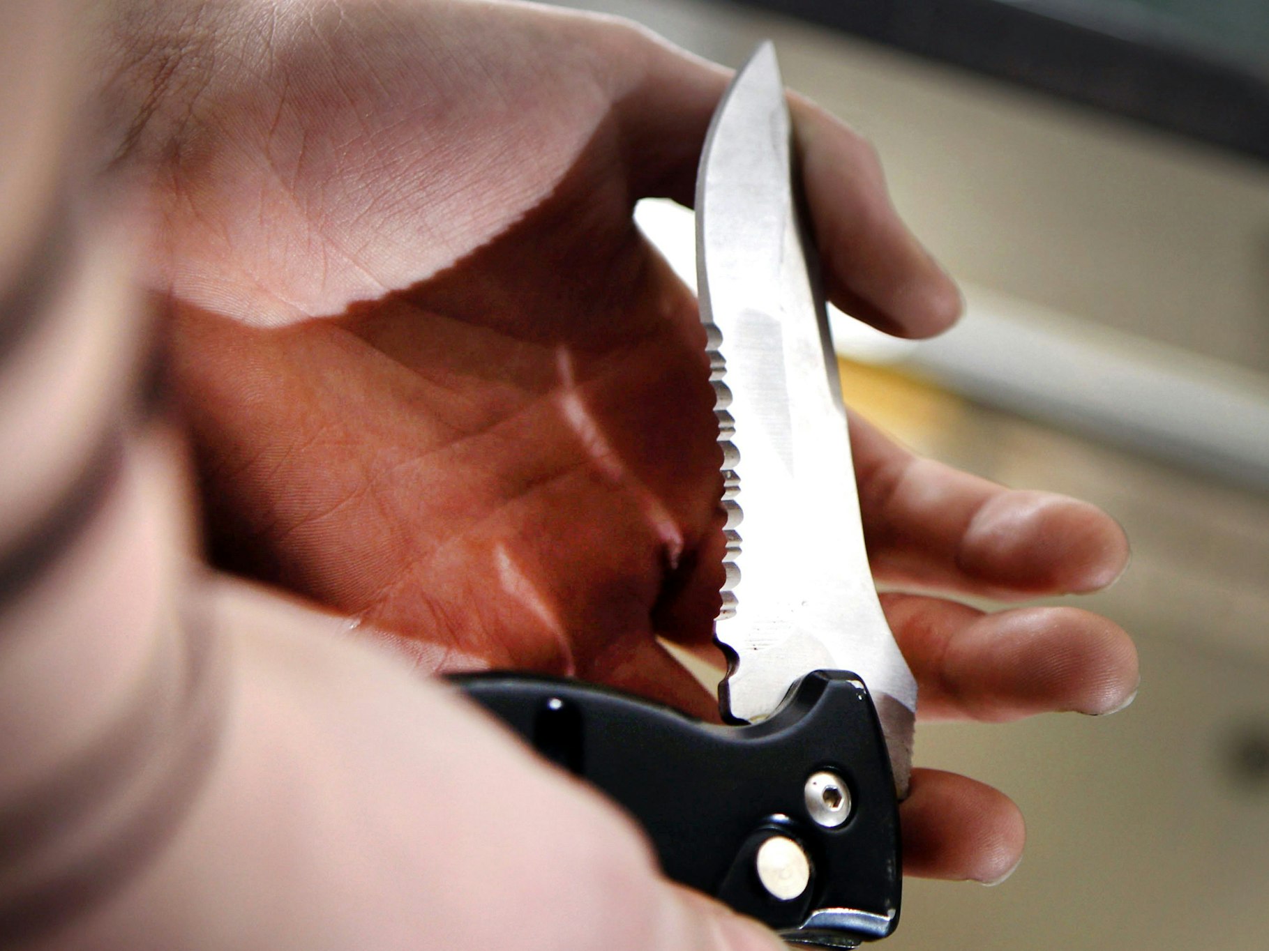 Eine Person hält ein Klappmesser mit schwarzem Griff in der Hand.